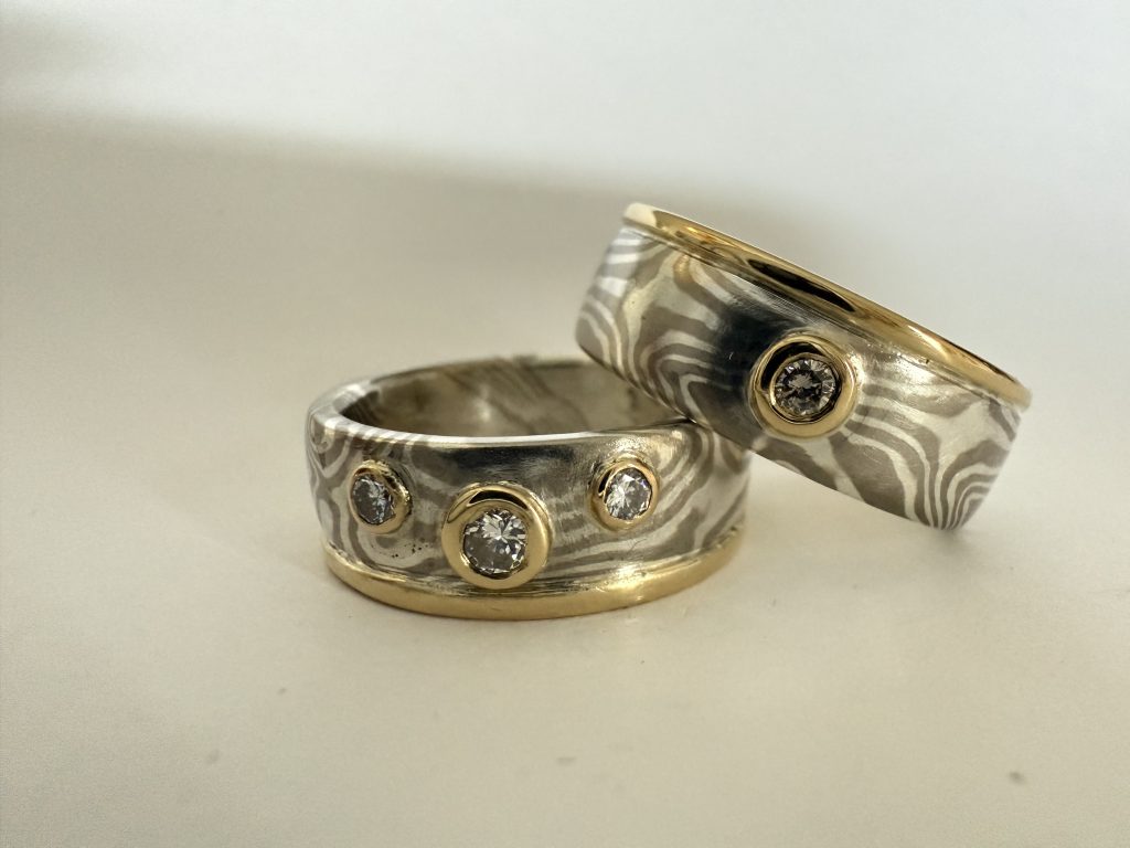 Mokume Gane Silber Palladium mit upcycling Goldrand und Fassung Mokume Gane Trauringe aus Silber und Palladium gewendet mit den Sternen aussen und einem Goldrand und goldenen Fassungen aus einem Familienschmuckstück